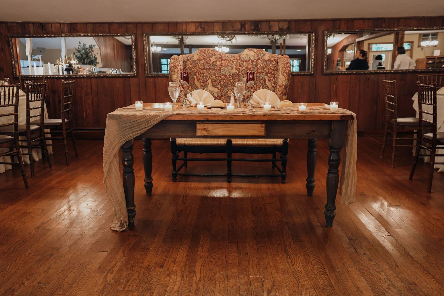 Interior view of an elegant restaurant dining room with wooden floors and tables set for service.