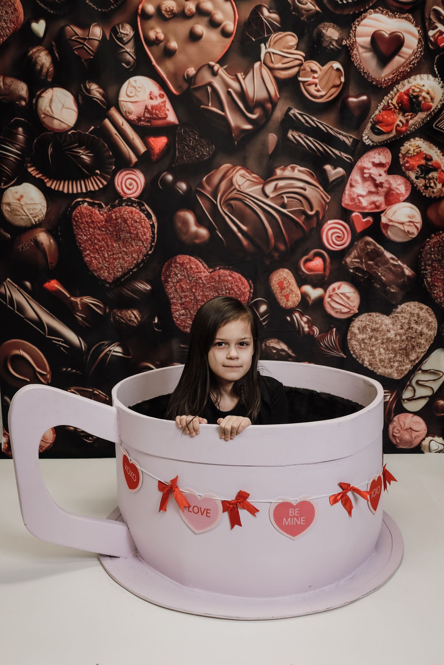 A creative Valentine's Day photo series showing a person peeking out from behind a white curved banner with heart decorations.