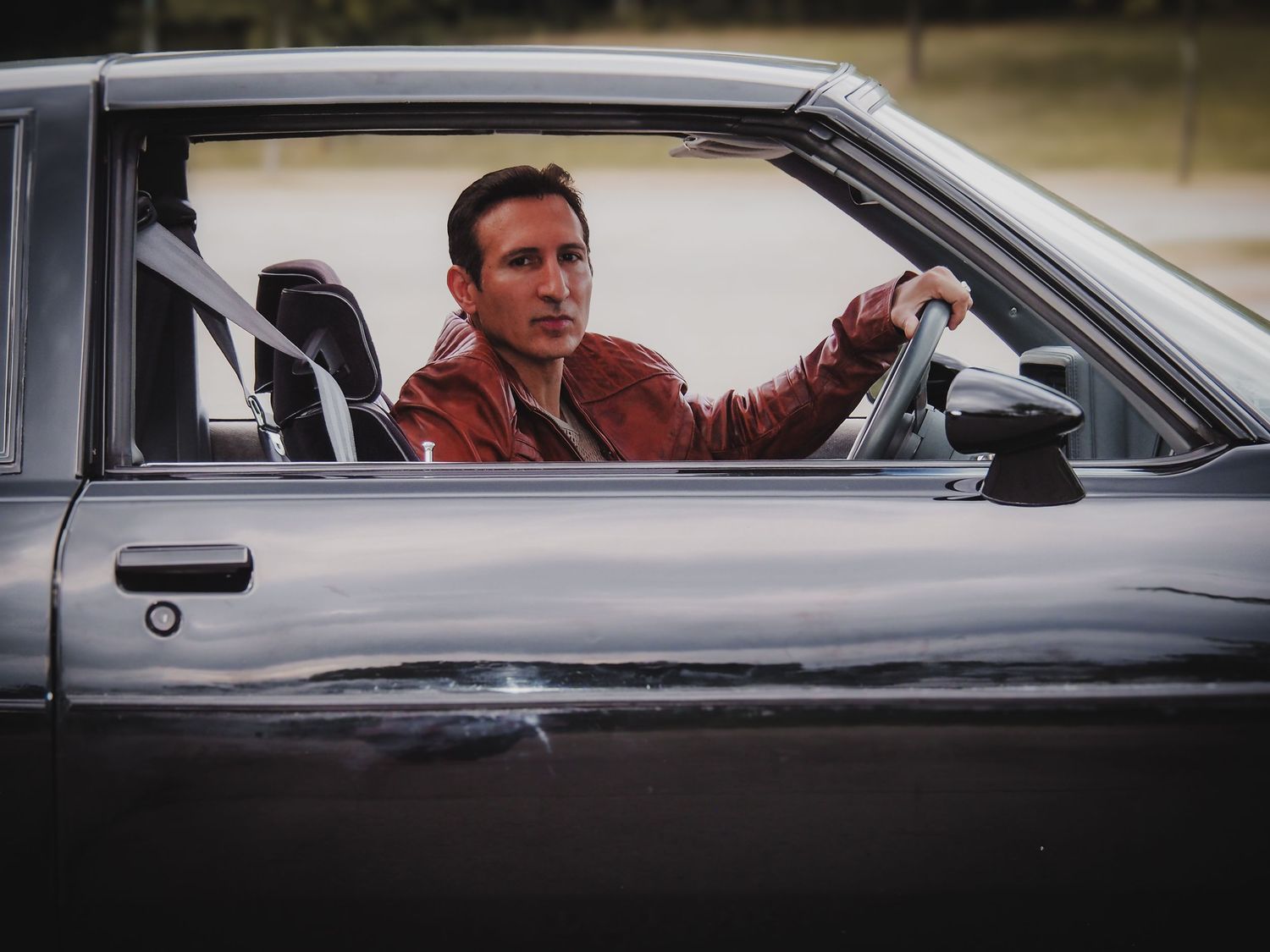 A series of black and white photographs showing someone sitting in a car looking through the driver's side window.