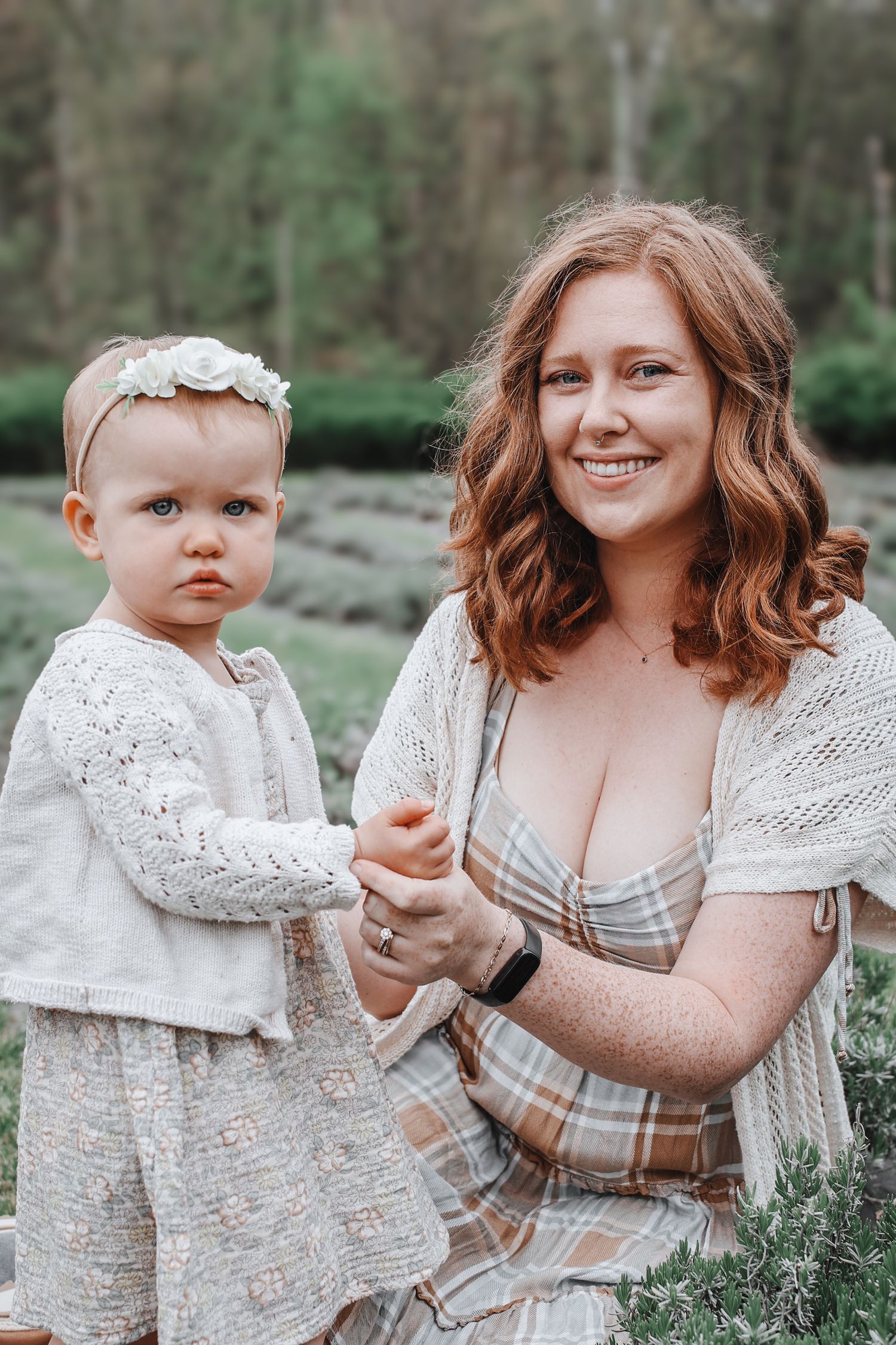 A mother and child wearing coordinated beige and white outfits pose outdoors in a natural setting.
