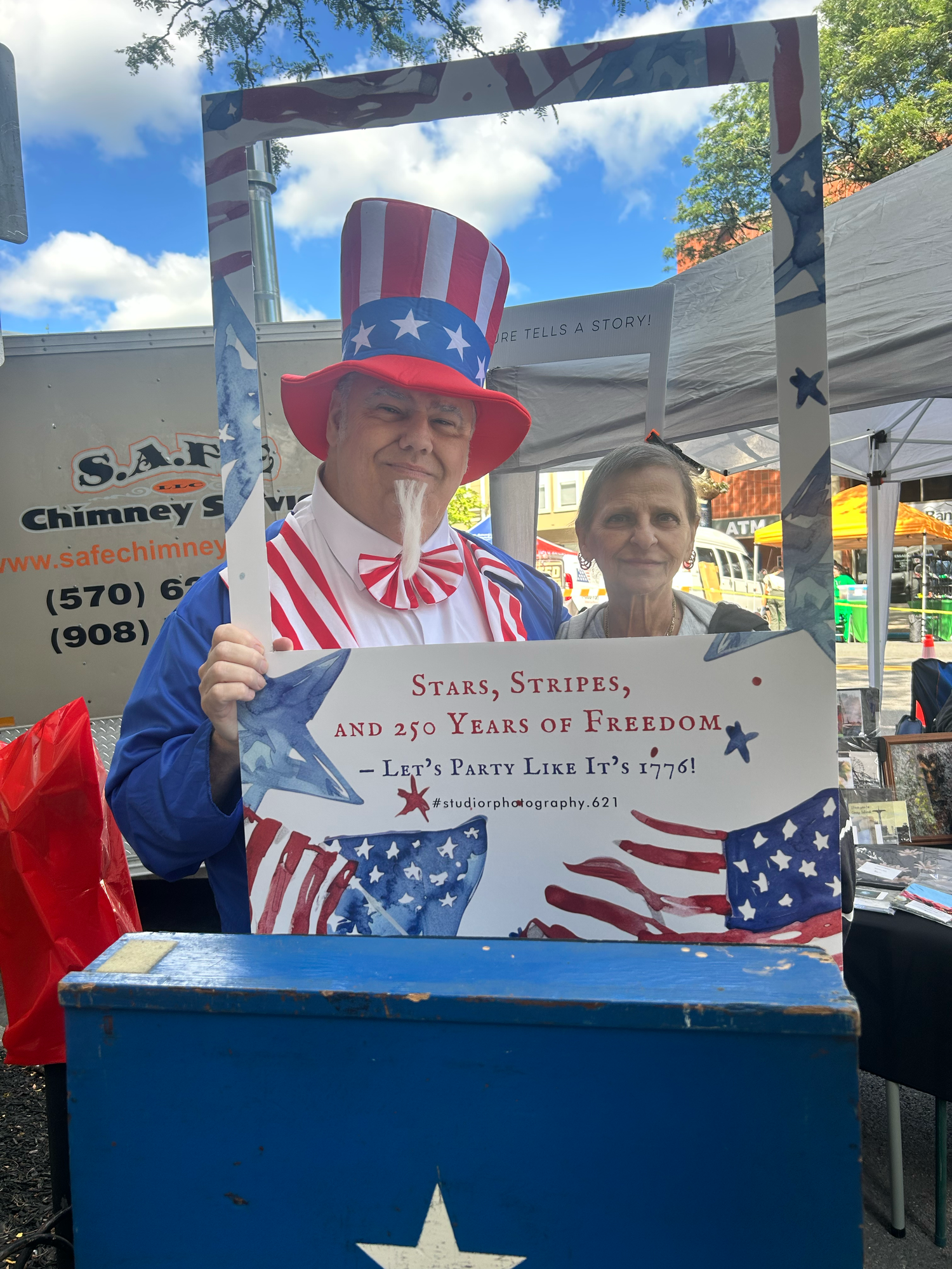 A patriotic display featuring red, white and blue decorations with American flags and banners against a storefront background.