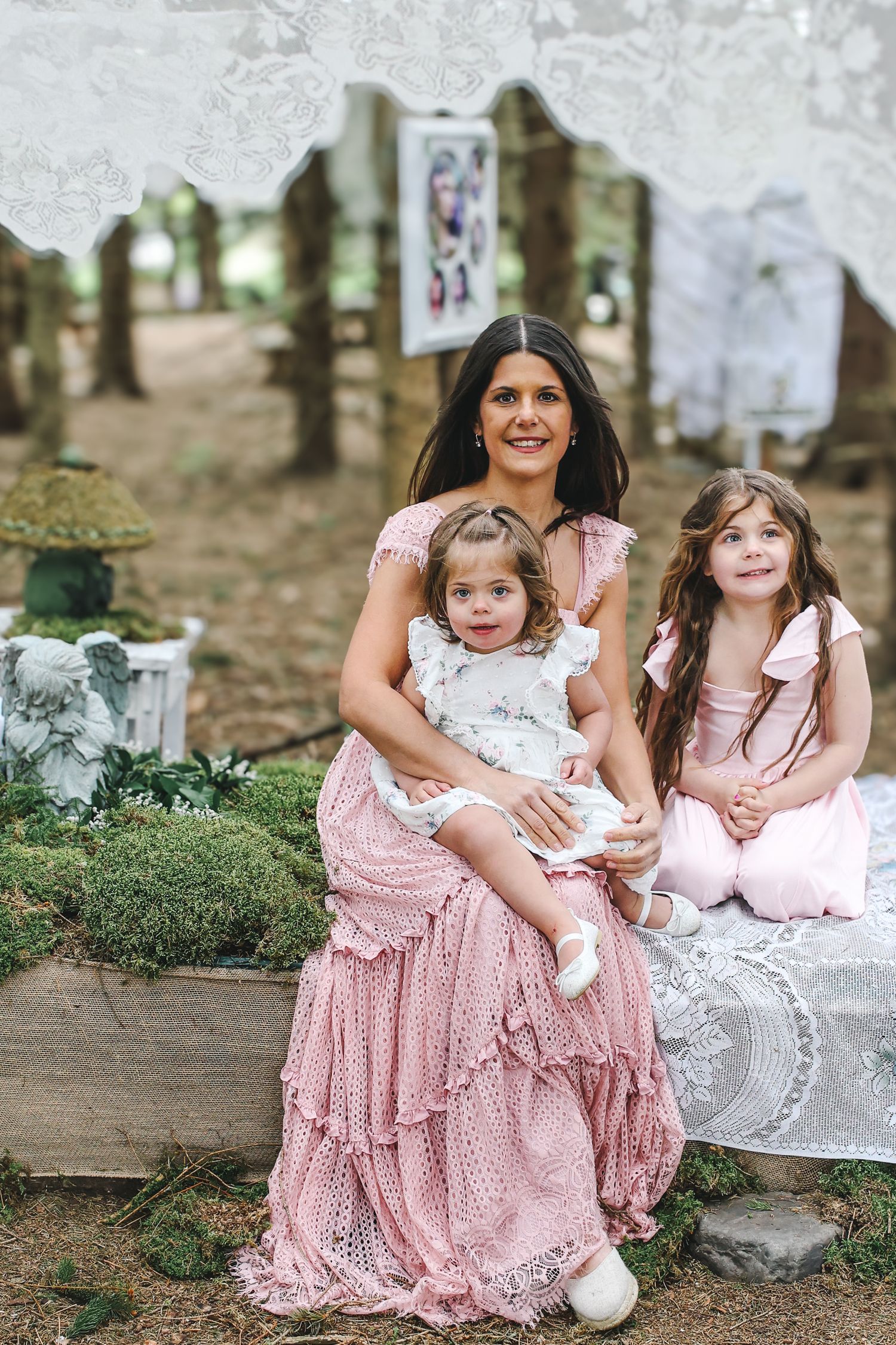 A series of outdoor family portraits featuring people in coordinating pink and white dresses sitting on rustic stone steps.
