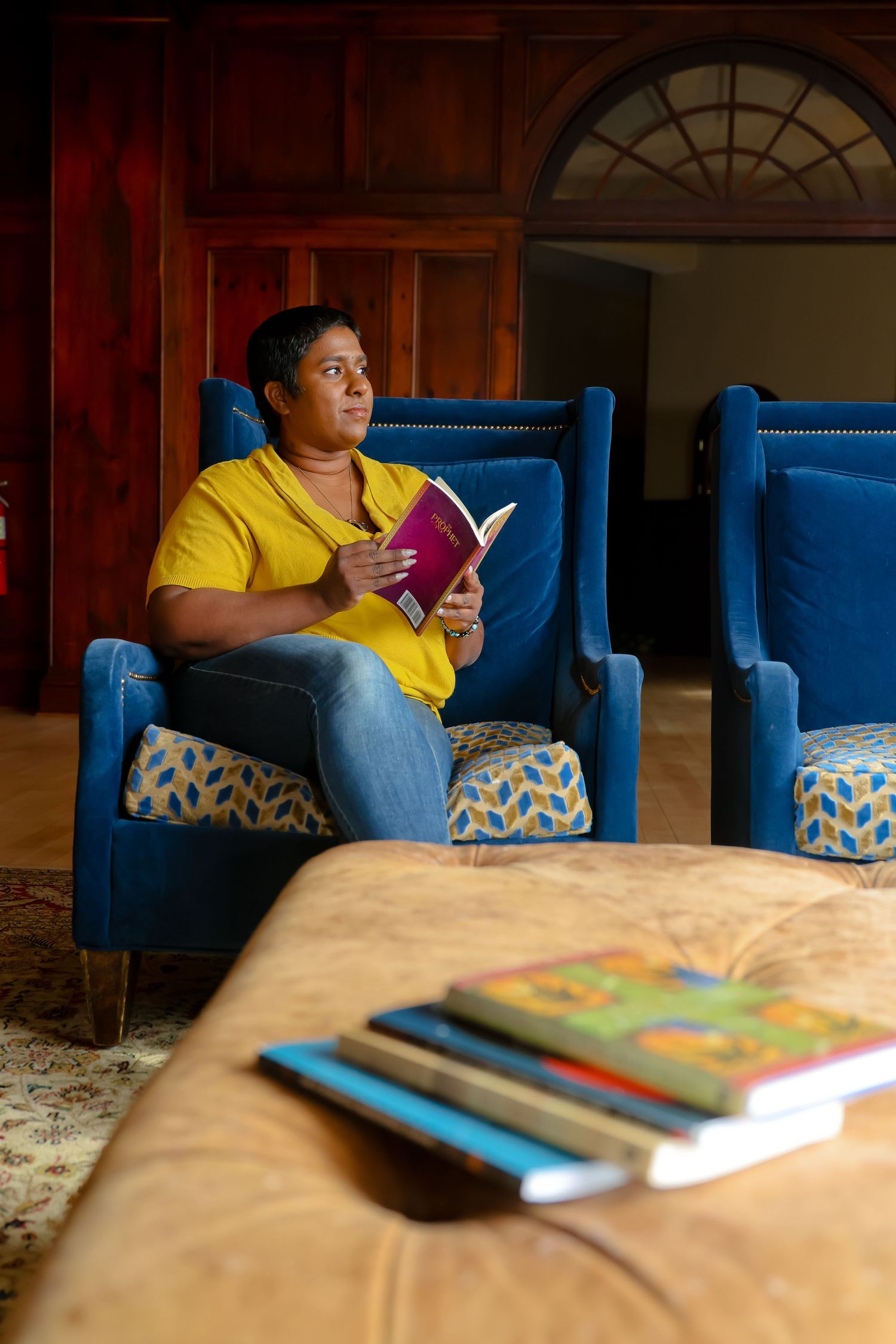 A sequence of photos showing someone in a yellow shirt reading a book while sitting on a bright blue armchair.