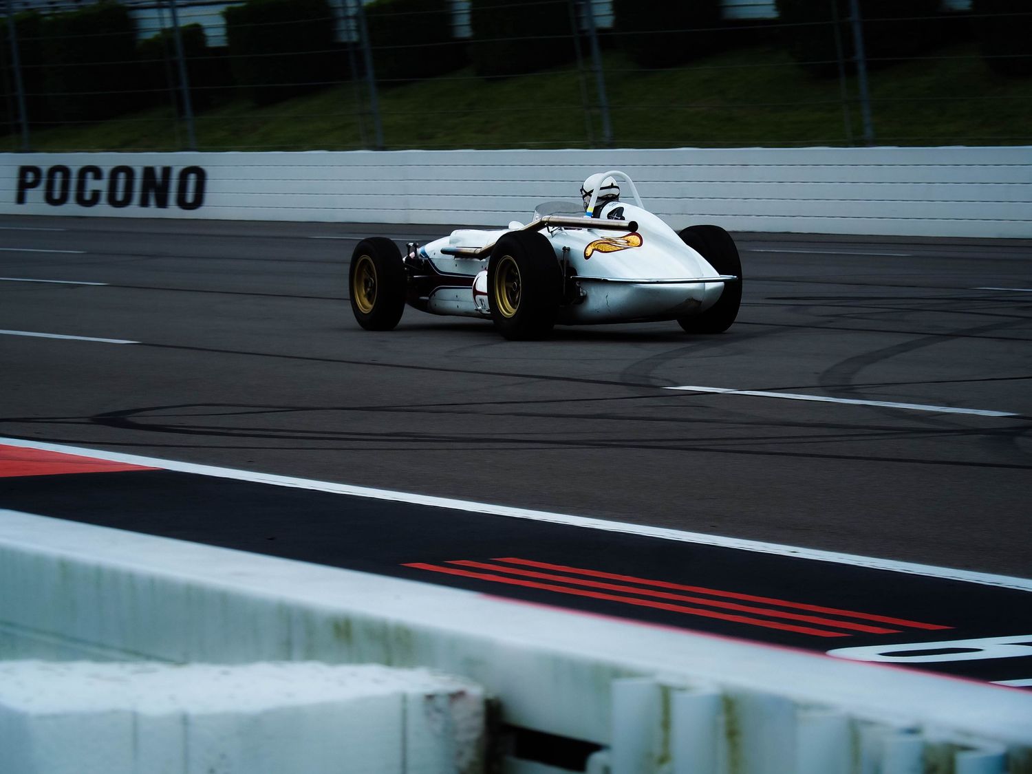 Racing cars speed around the Pocono Raceway track during a competitive motorsport event.