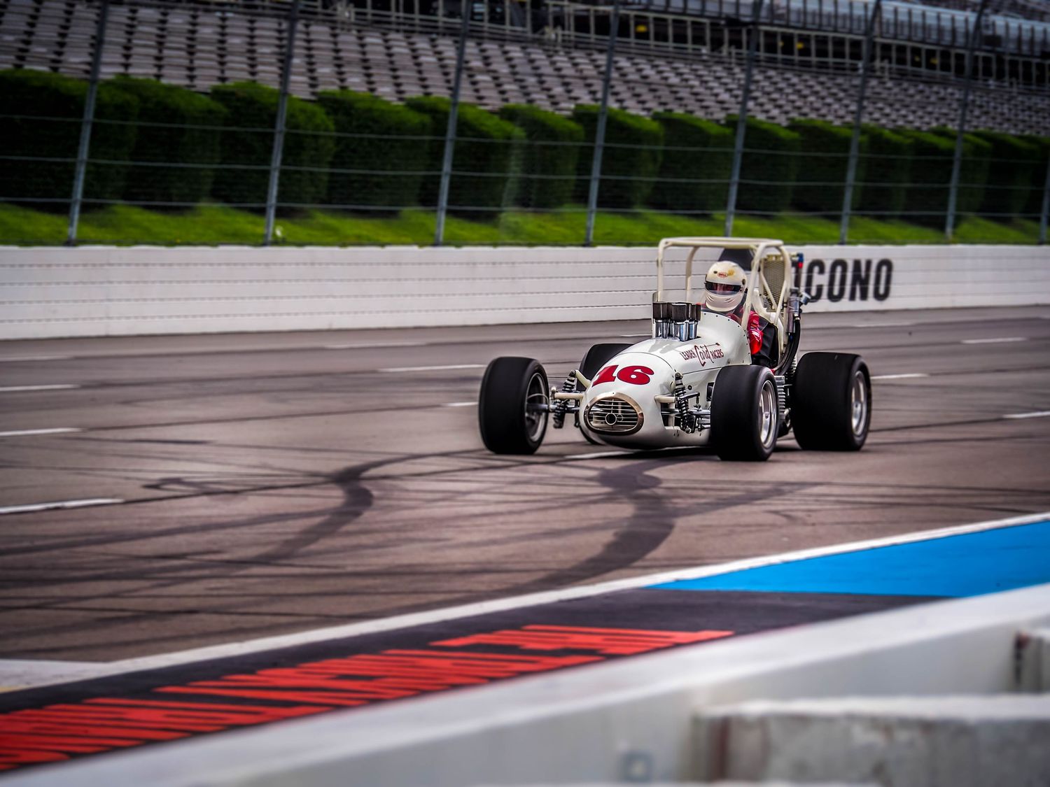 Formula One race car navigates through a winding track with red and blue curbs during a racing competition.