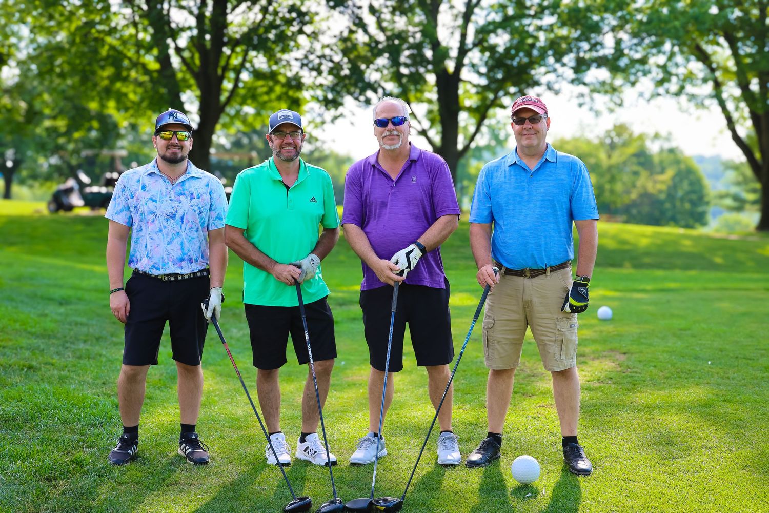 Group of golfers walking together on a lush green golf course during a sunny afternoon.