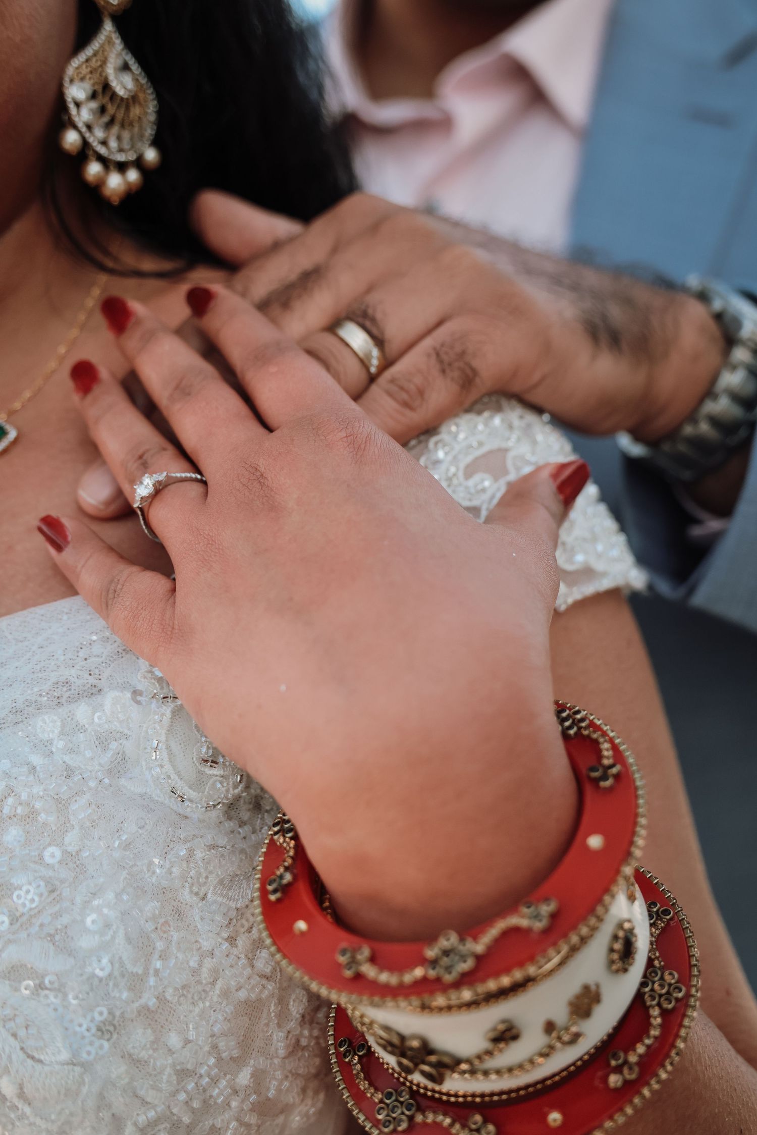 Close-up of hands with red nails and traditional Indian wedding bangles and jewelry.
