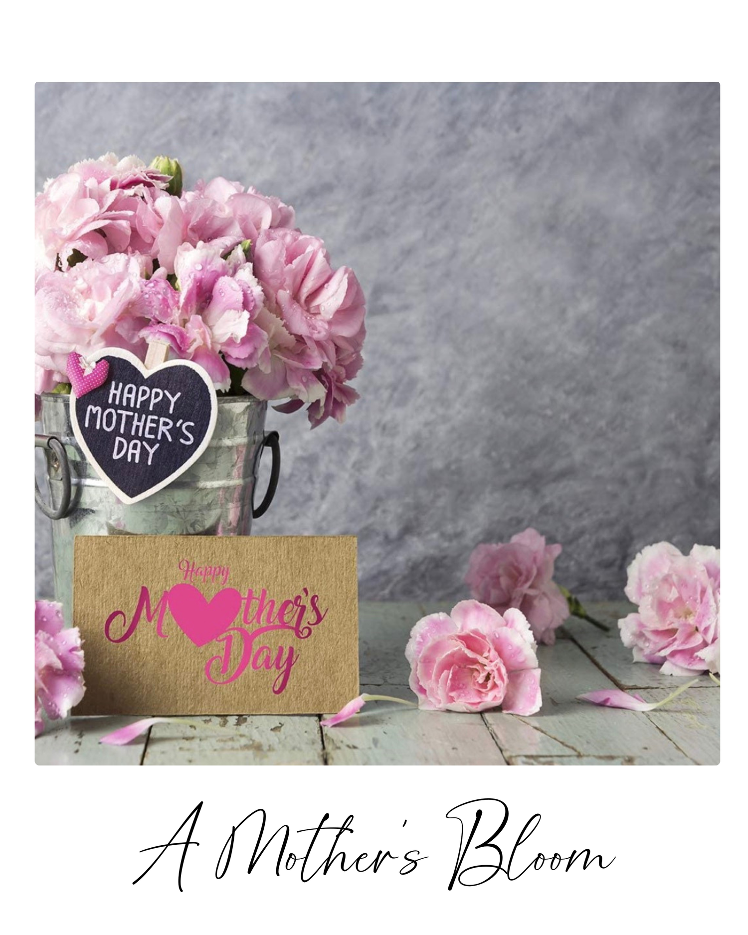 Pink roses in a rustic vase with a Mother's Day heart sign and wooden greeting card on gray background.