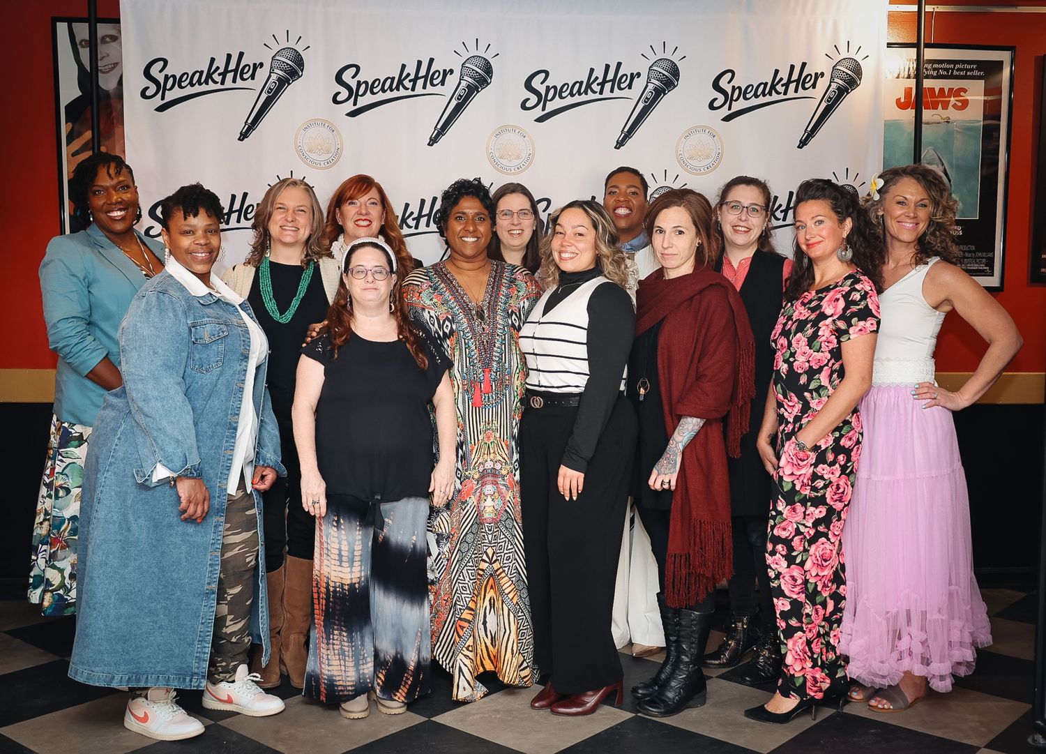 Group of women posing together at a SpeakHer event, smiling in front of a branded backdrop.