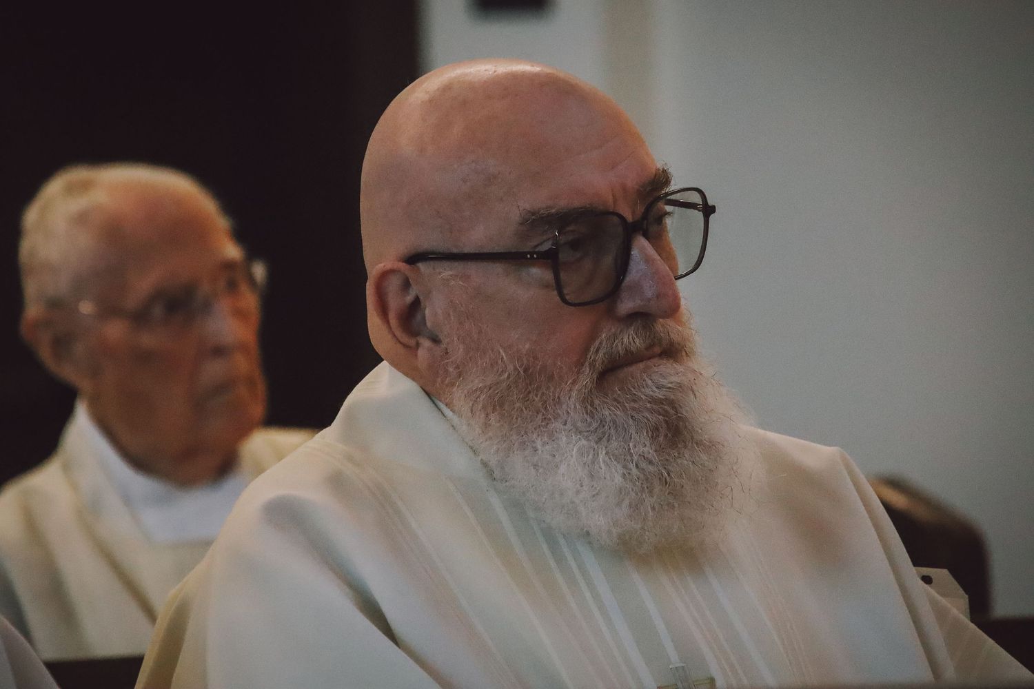 A group of elderly individuals with beards and glasses sitting together in an indoor setting.