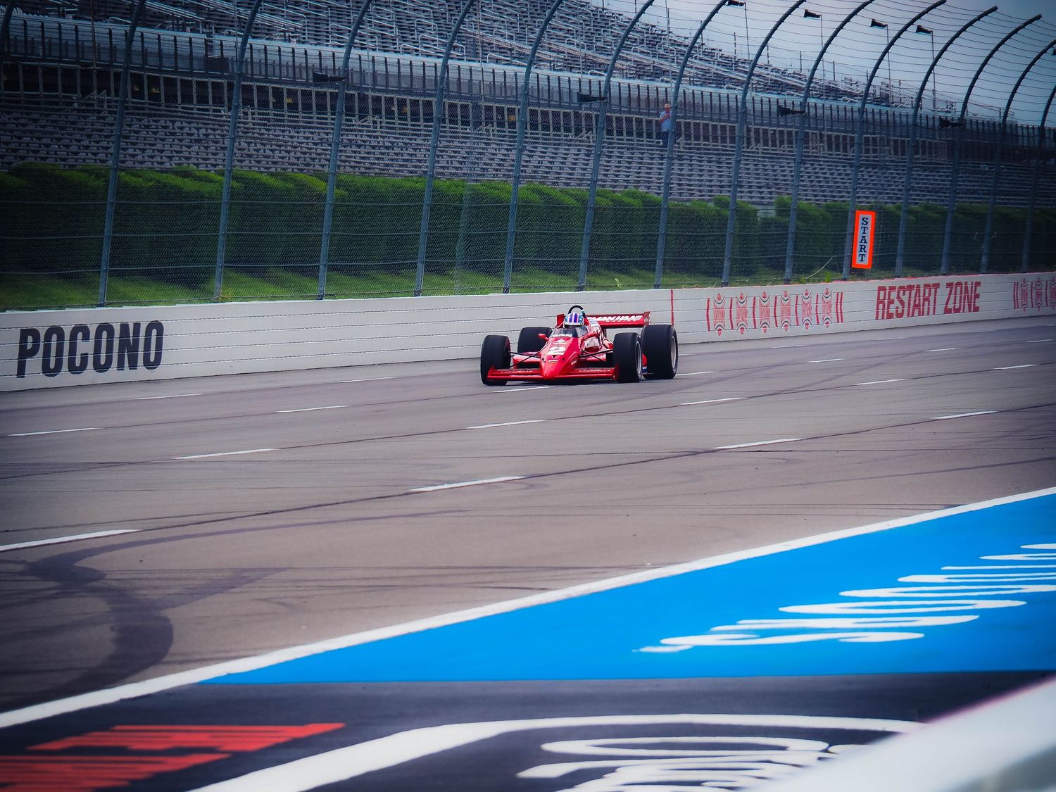 Red IndyCar races around the banked turn at Pocono Raceway during a practice session.