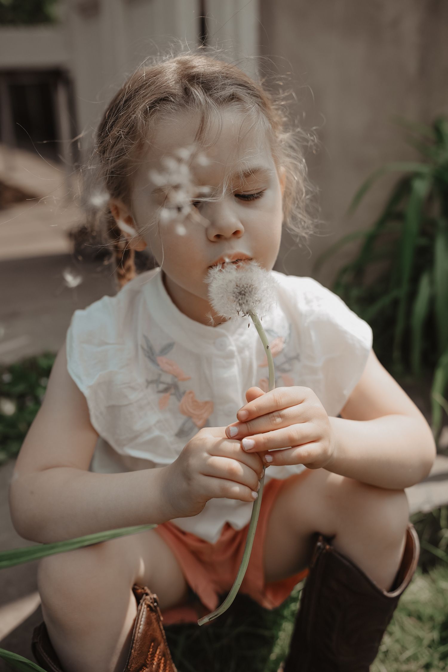 A child in a white dress blows bubbles in a series of four connected photos showing the playful sequence.