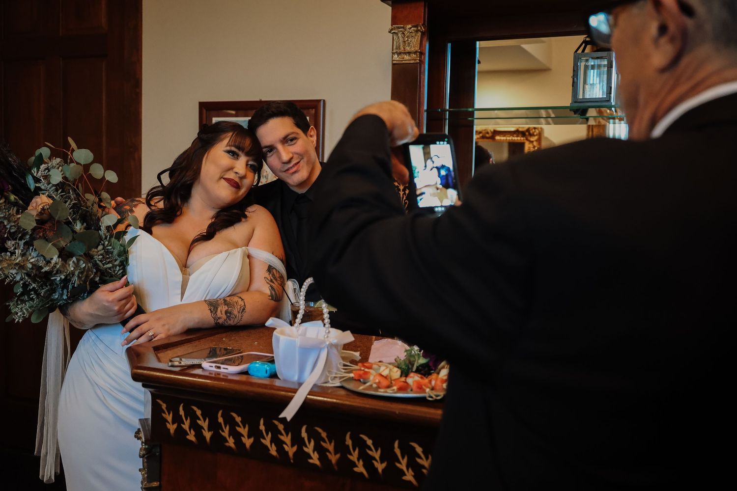 A couple shares an intimate moment at a restaurant table while looking at their phones together.