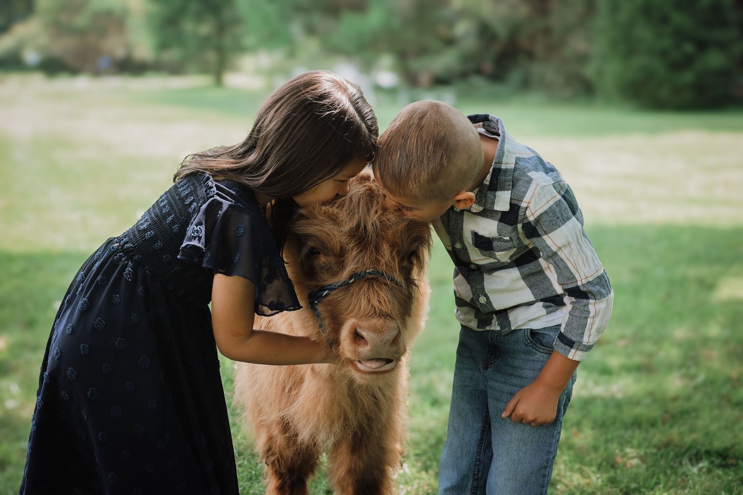 A couple embraces in a romantic outdoor setting surrounded by lush green trees and grass.
