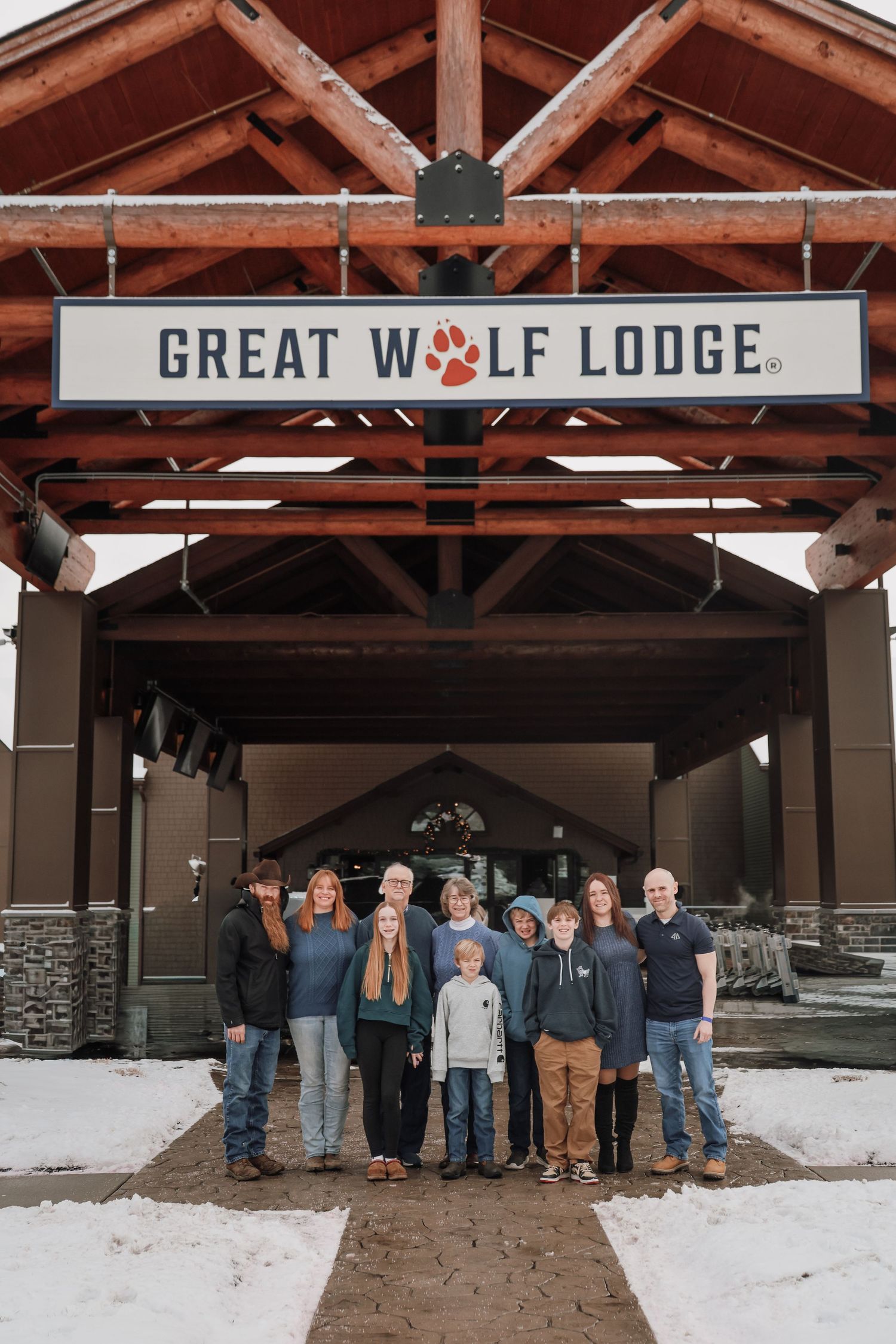 A group of people standing in front of the Great Wolf Lodge entrance during winter with snow on the ground.