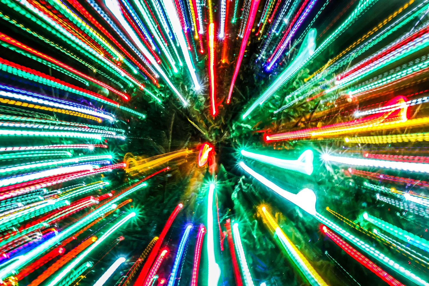 Colorful light trails burst outward in a radial pattern creating a vibrant abstract pattern of streaking neon colors.