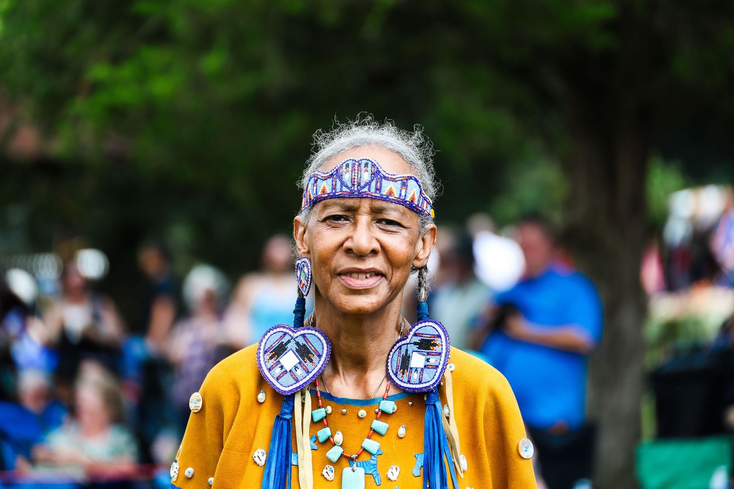 A person wearing traditional Native American regalia and headband performs during a cultural celebration outdoors.