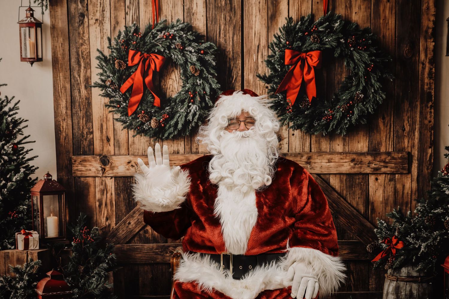 Rustic wooden wall decorated with evergreen Christmas wreaths adorned with red bows and holiday decor.