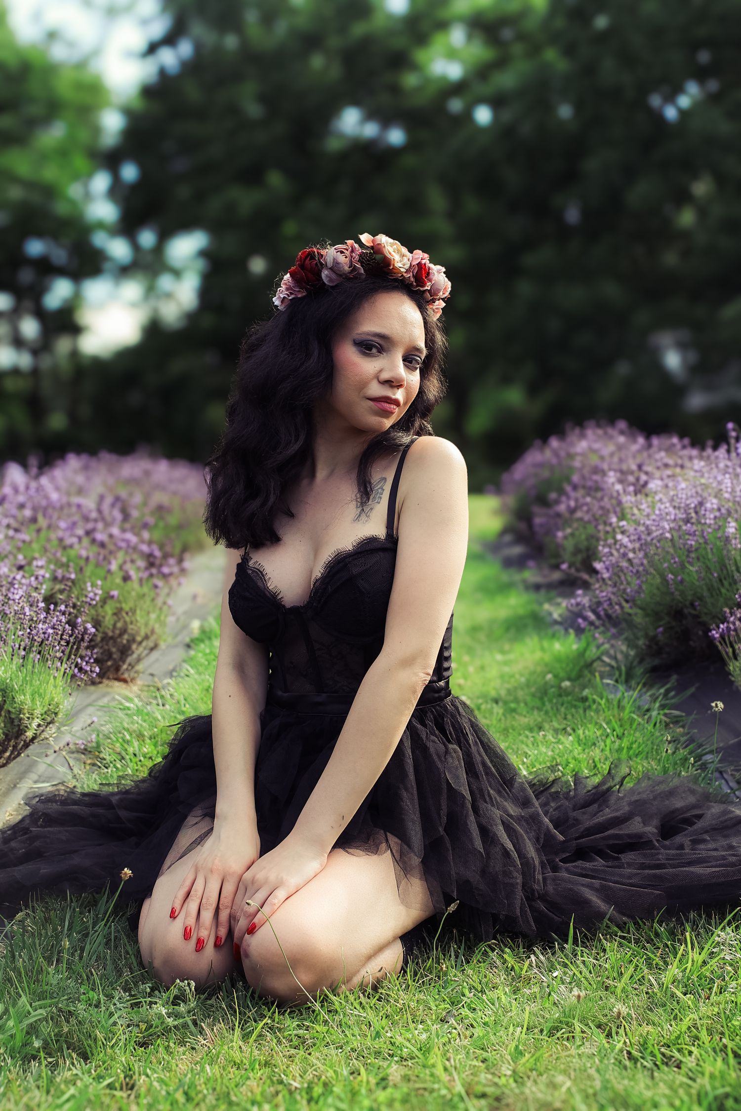 Ethereal portrait in a lavender field featuring a black tulle dress and floral crown against lush greenery.