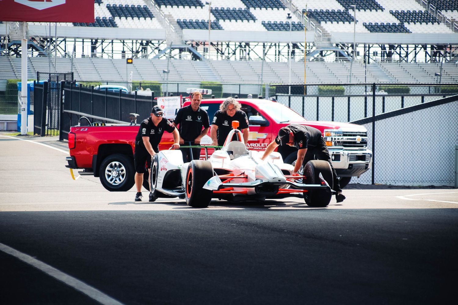 A group of red and white sports cars parked in a row at a racing track event.