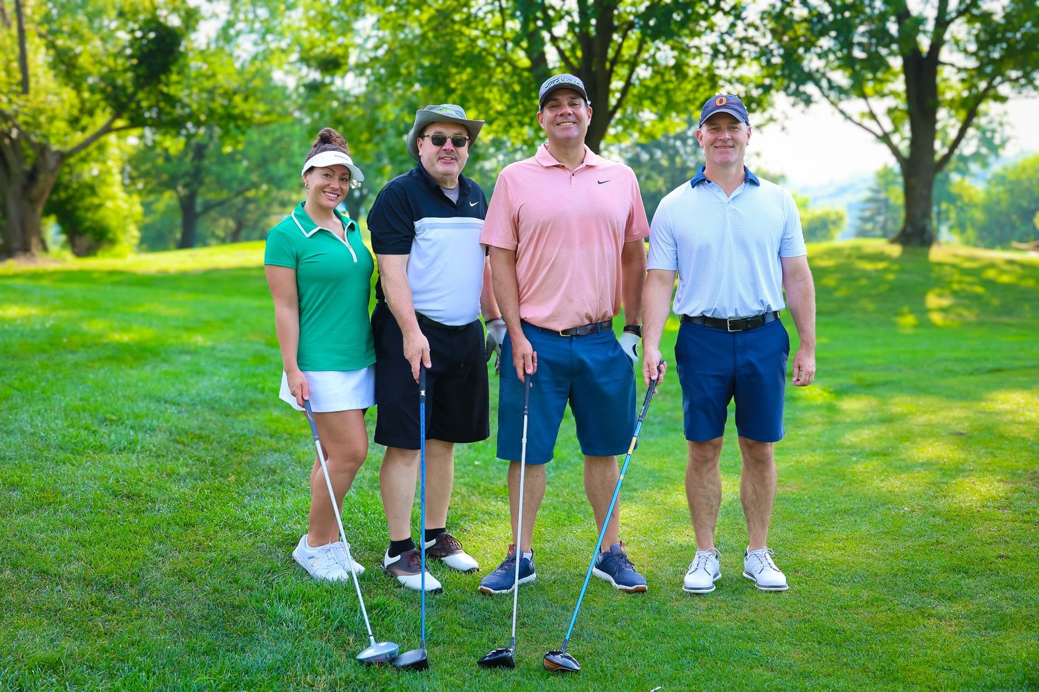 Group of golfers walking together on a lush green golf course during a sunny summer day.