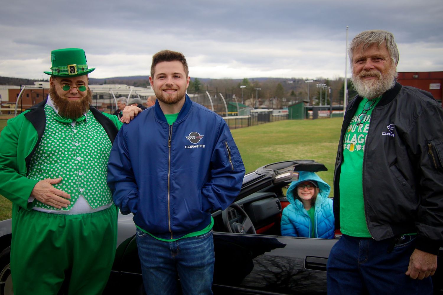 People wearing green clothing and accessories gather outdoors to celebrate St Patrick's Day festivities.