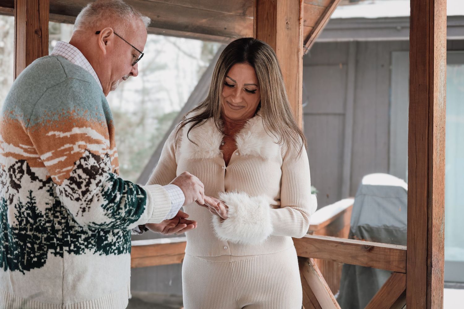 Two people review paperwork together while standing in a covered wooden porch area.