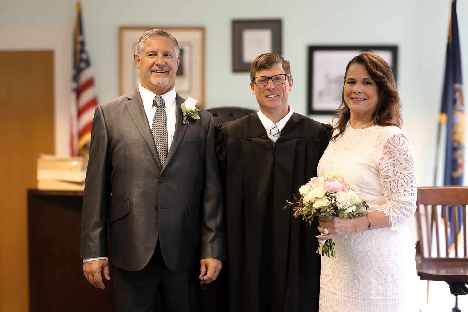 A wedding ceremony takes place in a courthouse with the couple and officiant standing together in formal attire.