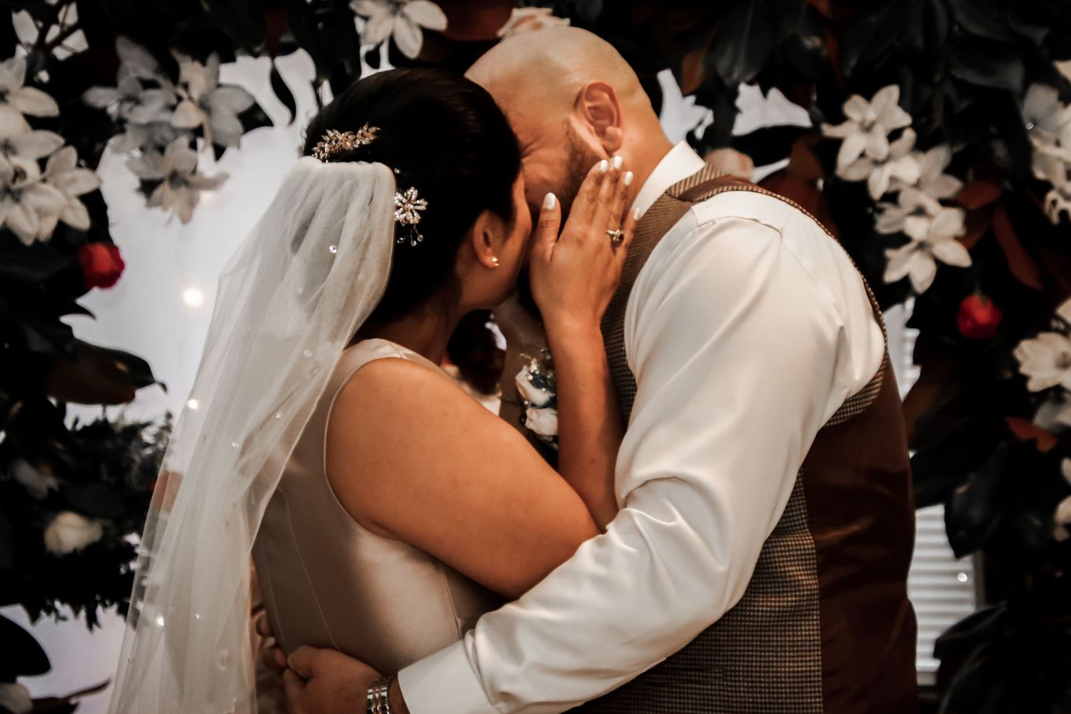 Romantic wedding photo collage showing tender moments between newlyweds with white floral decorations in the background.