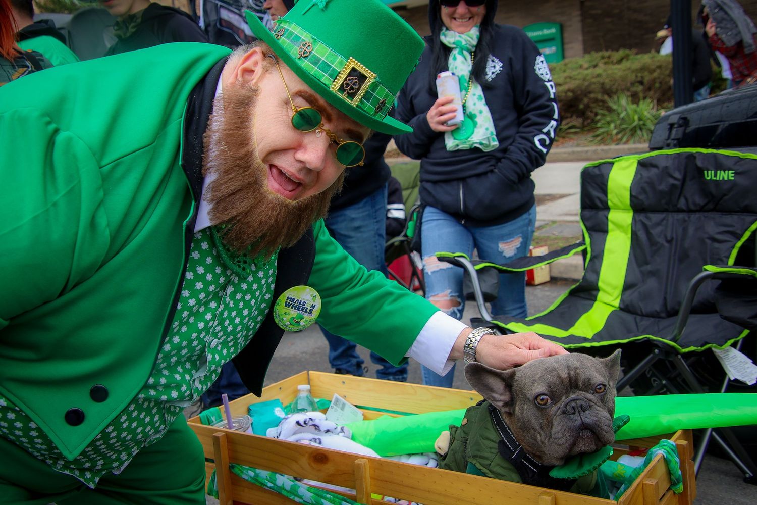 People wearing green St. Patrick's Day attire celebrate at an outdoor gathering with food and drinks.