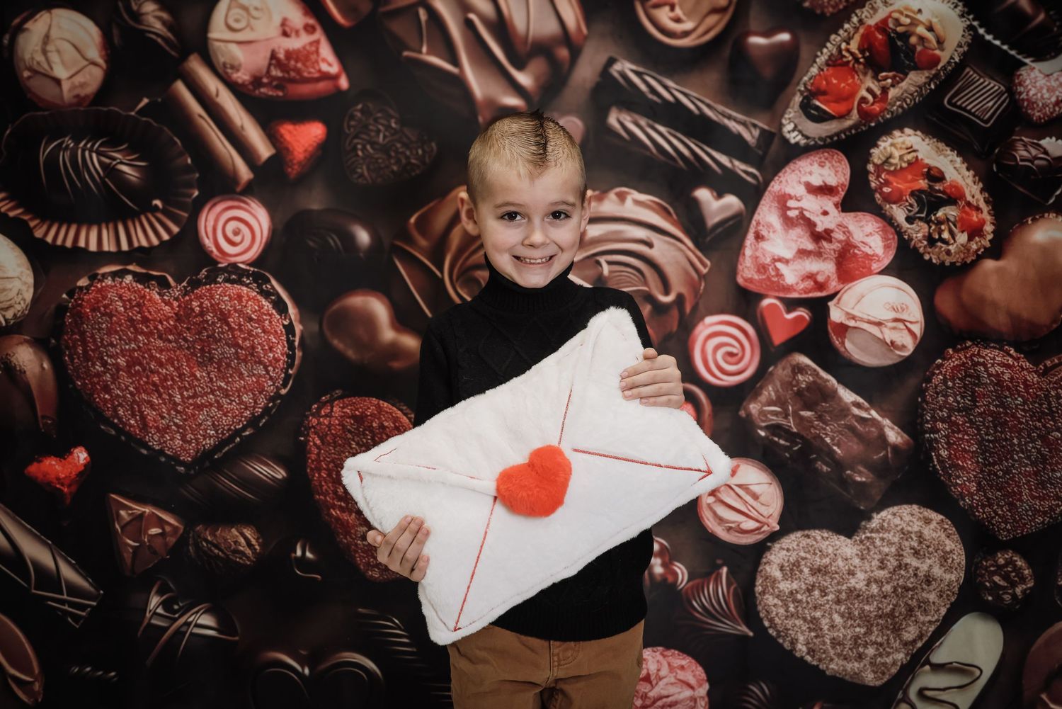 Assorted chocolate truffles, candies and heart-shaped sweets arranged on a dark background with red accents.