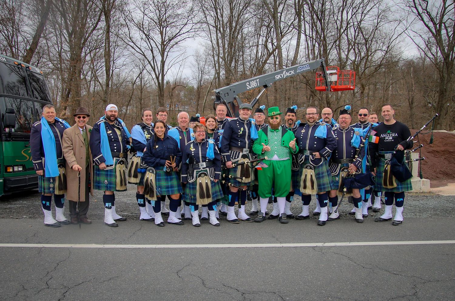 A line of people in matching blue and white uniforms stand together outdoors during a group photo session.