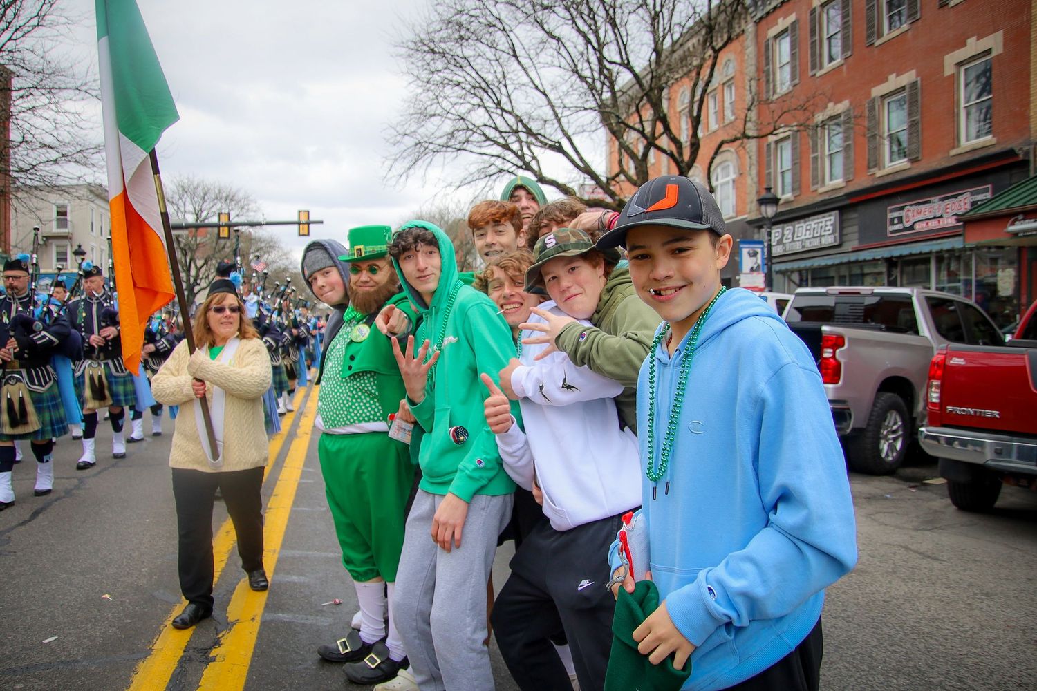 People in green and blue clothing celebrate St Patrick's Day at a festive street parade.