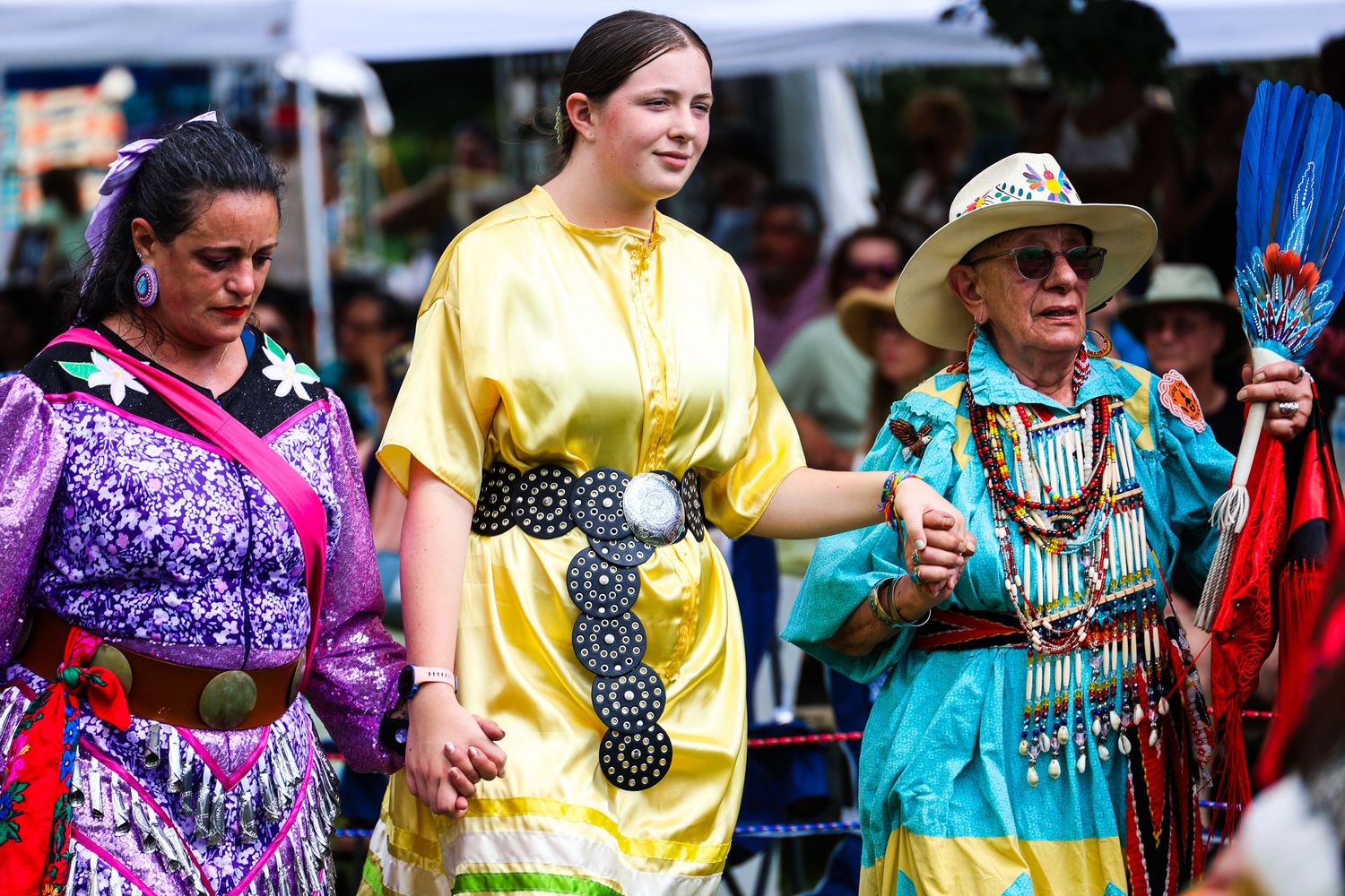 Colorful powwow dancers in traditional regalia perform at an outdoor Native American cultural celebration.