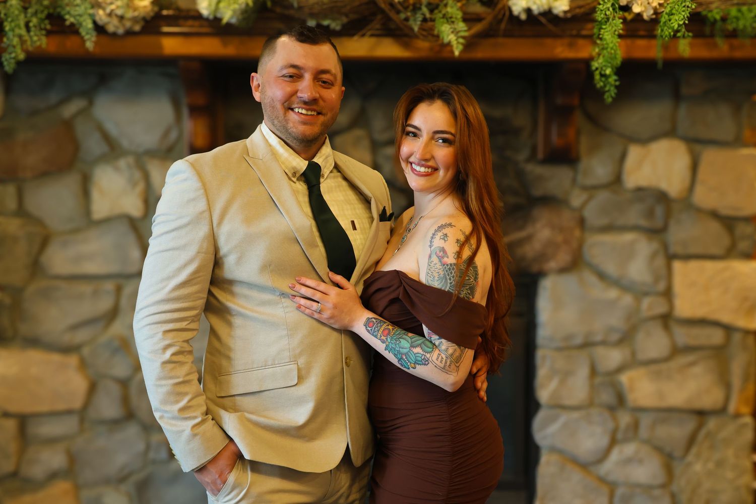 Happy couple shares joyful moments together against stone wall backdrop during outdoor photo session.