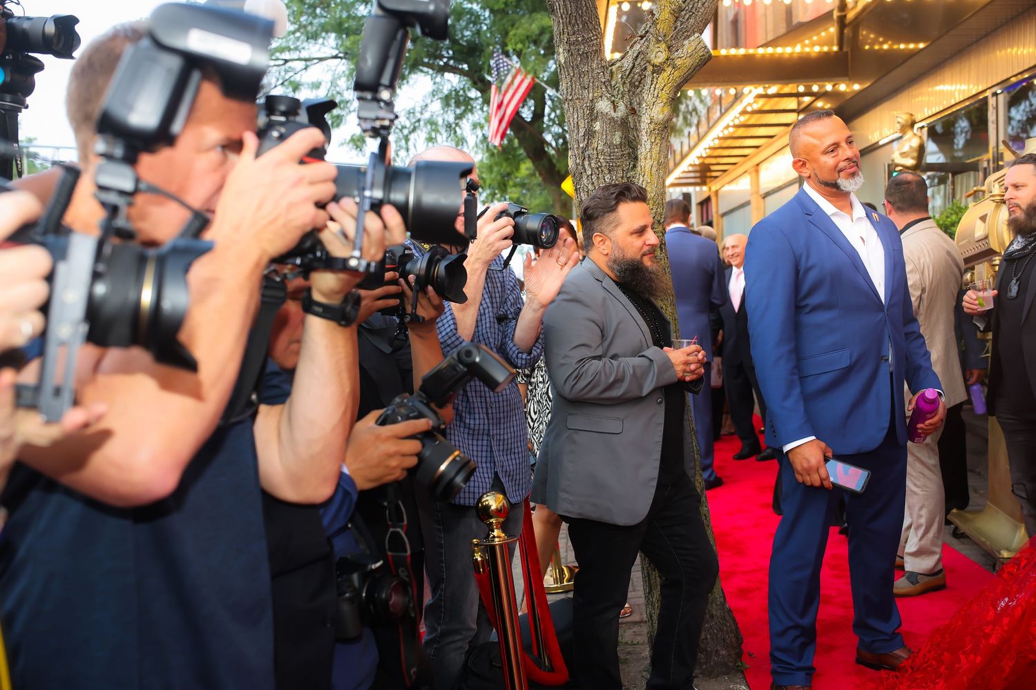 Media and press photographers gather with cameras and equipment at a red carpet event.