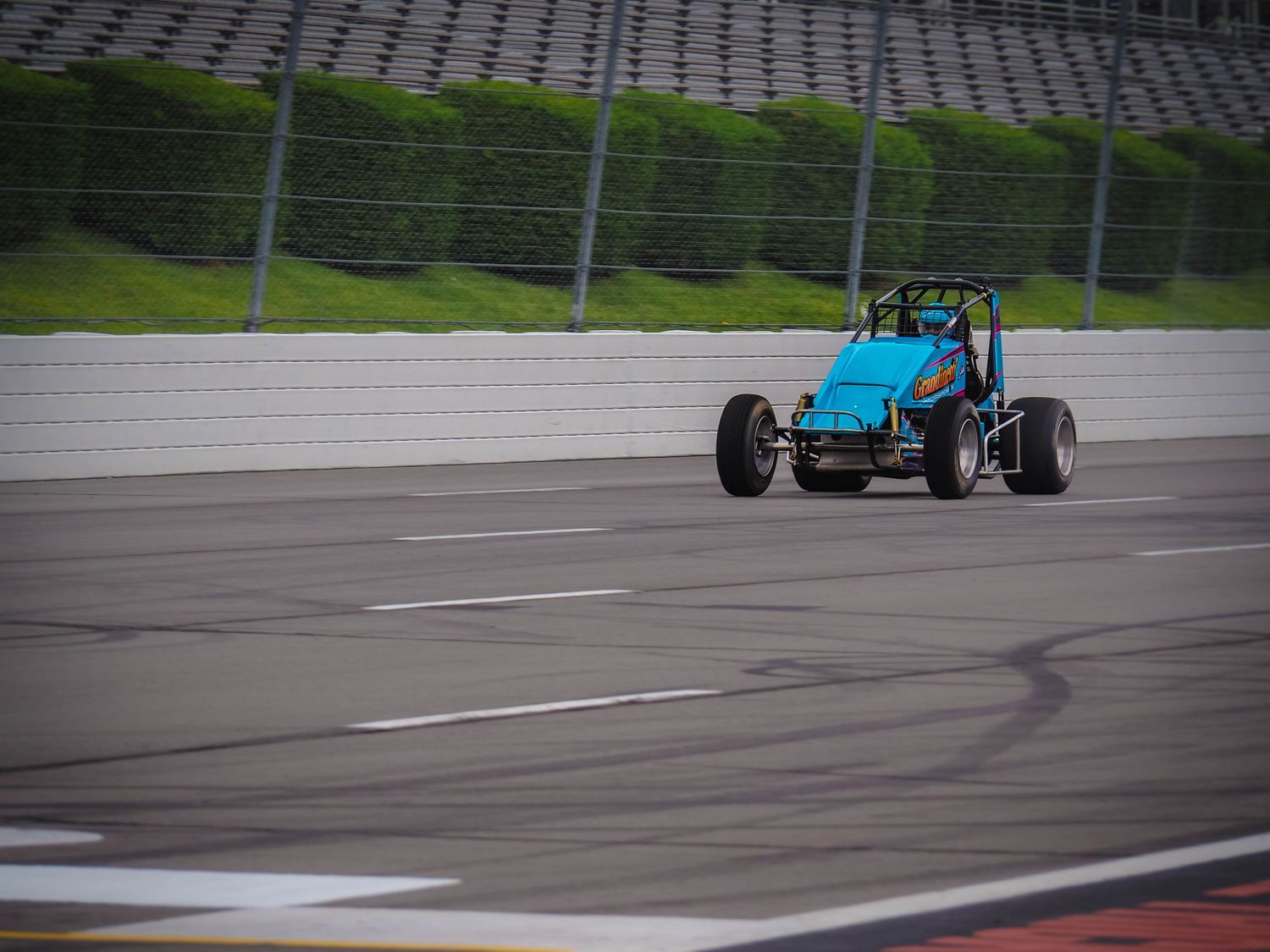 Formula-style race cars navigate a wet racetrack during a competitive motorsport event.