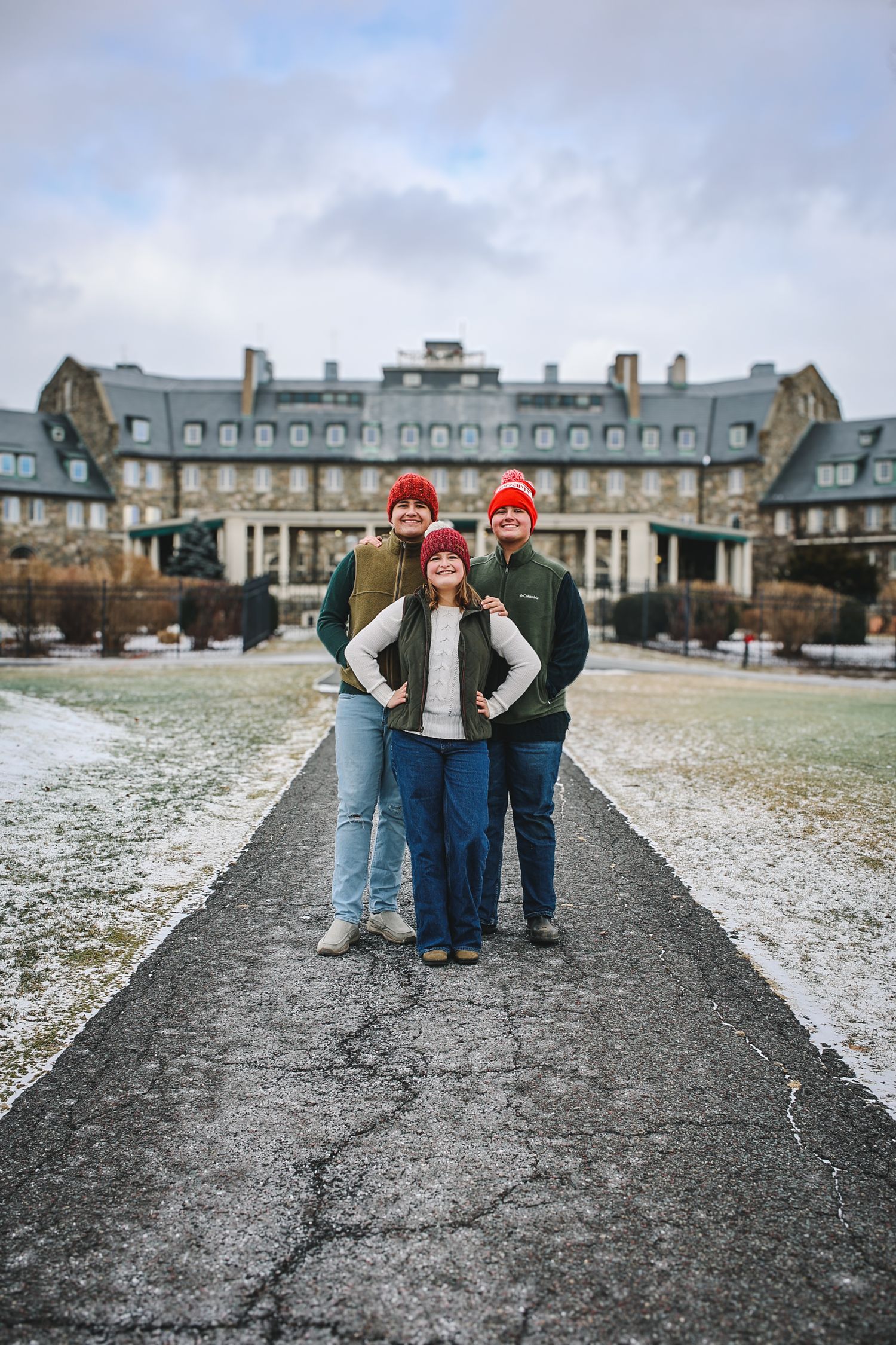 A group of friends stand together on a snowy path with historic buildings in the background.