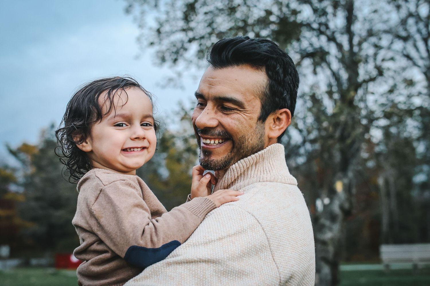 Father and child share joyful moments together outdoors during an autumn photoshoot.