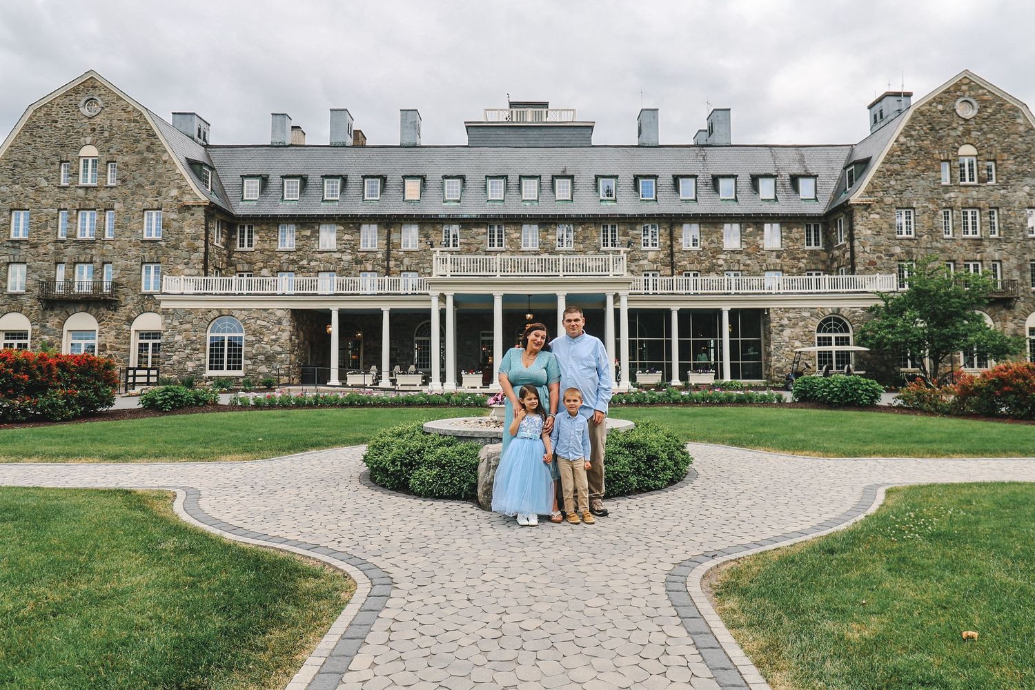 Panoramic view of a historic stone building with elegant columns and a curved driveway entrance.