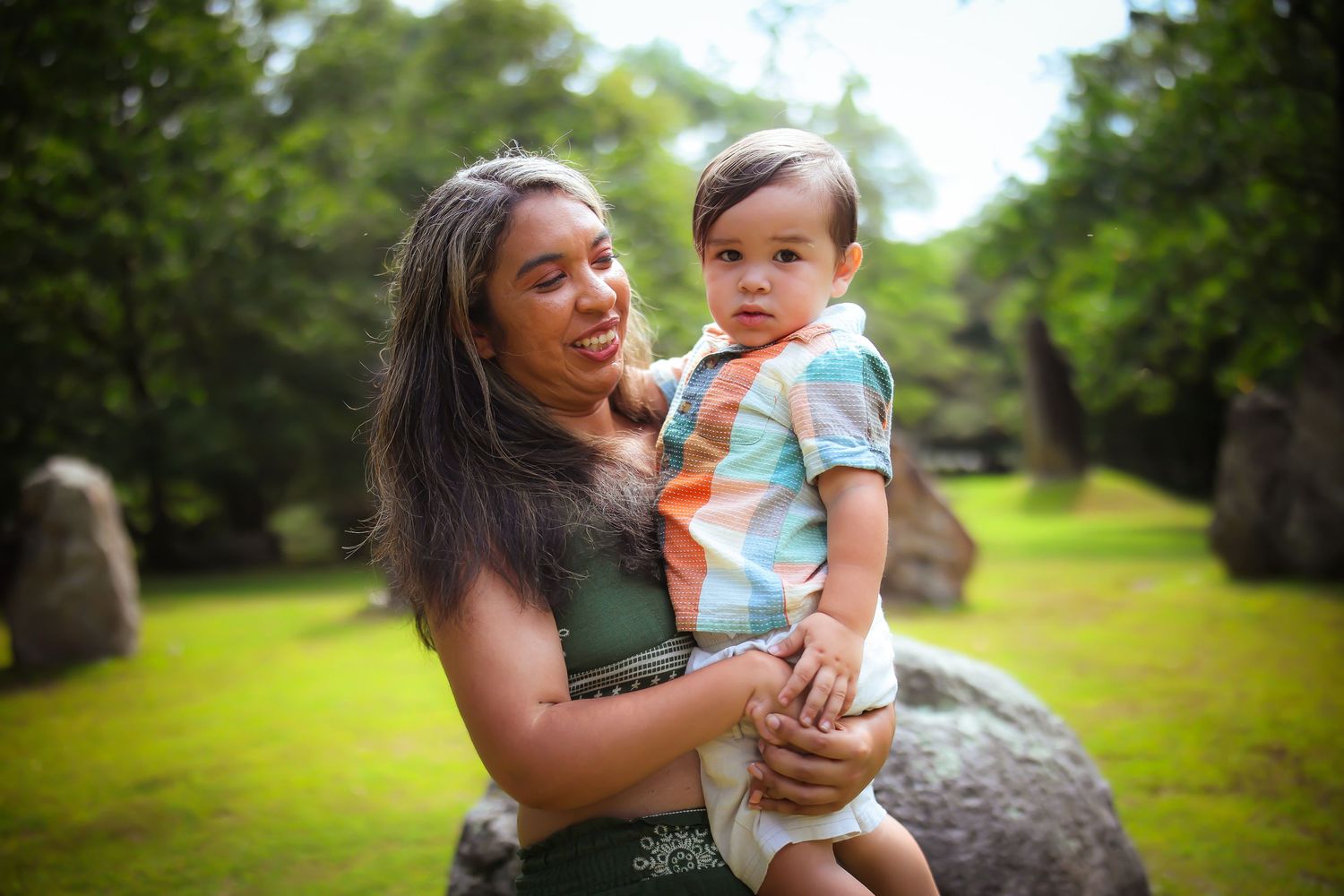 A series of outdoor portraits showing a parent and baby bonding together in a lush green park setting.