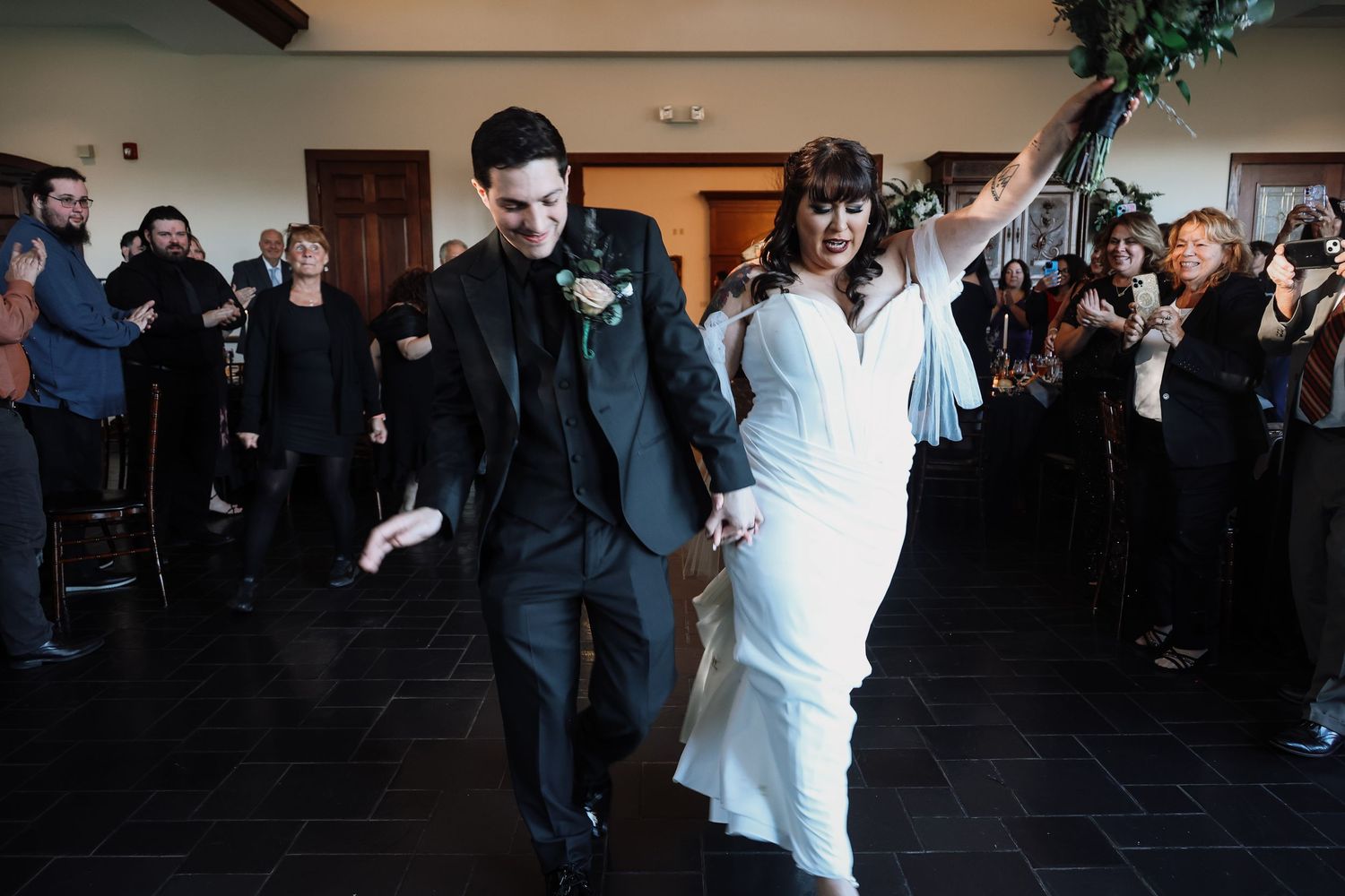A couple shares a romantic dance at a wedding reception while guests look on in the background.