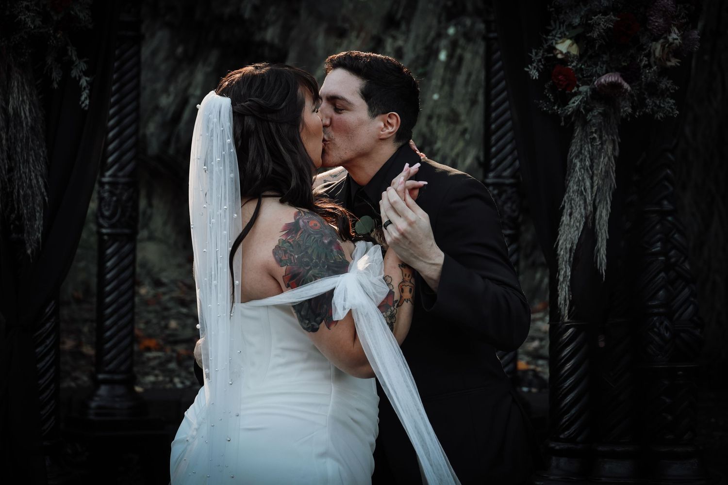 A romantic wedding couple shares intimate moments in a dark wooded setting during their photo session.
