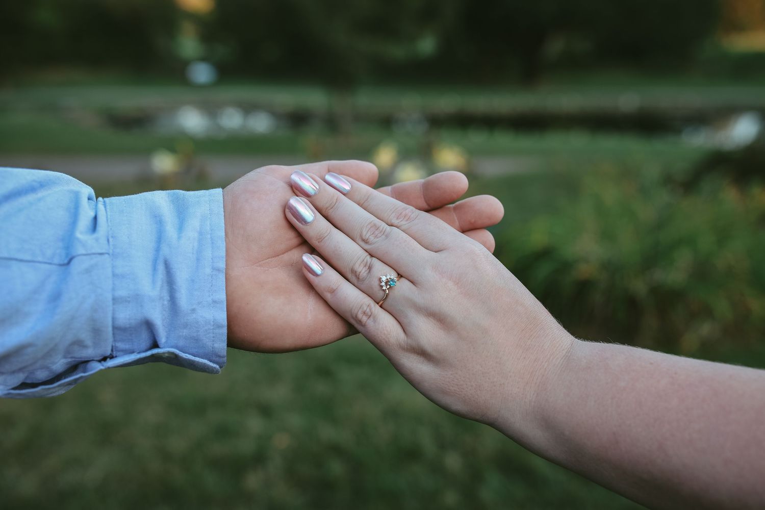 A series of hands reaching out to connect with each other in a natural outdoor setting.