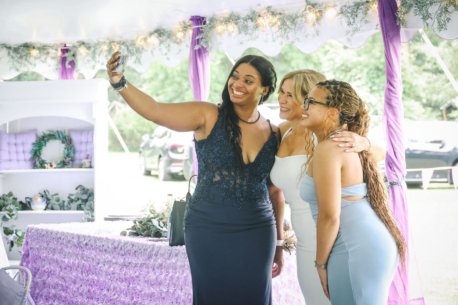 Wedding celebration with purple decorations showing guests taking photos and sharing joyful moments.