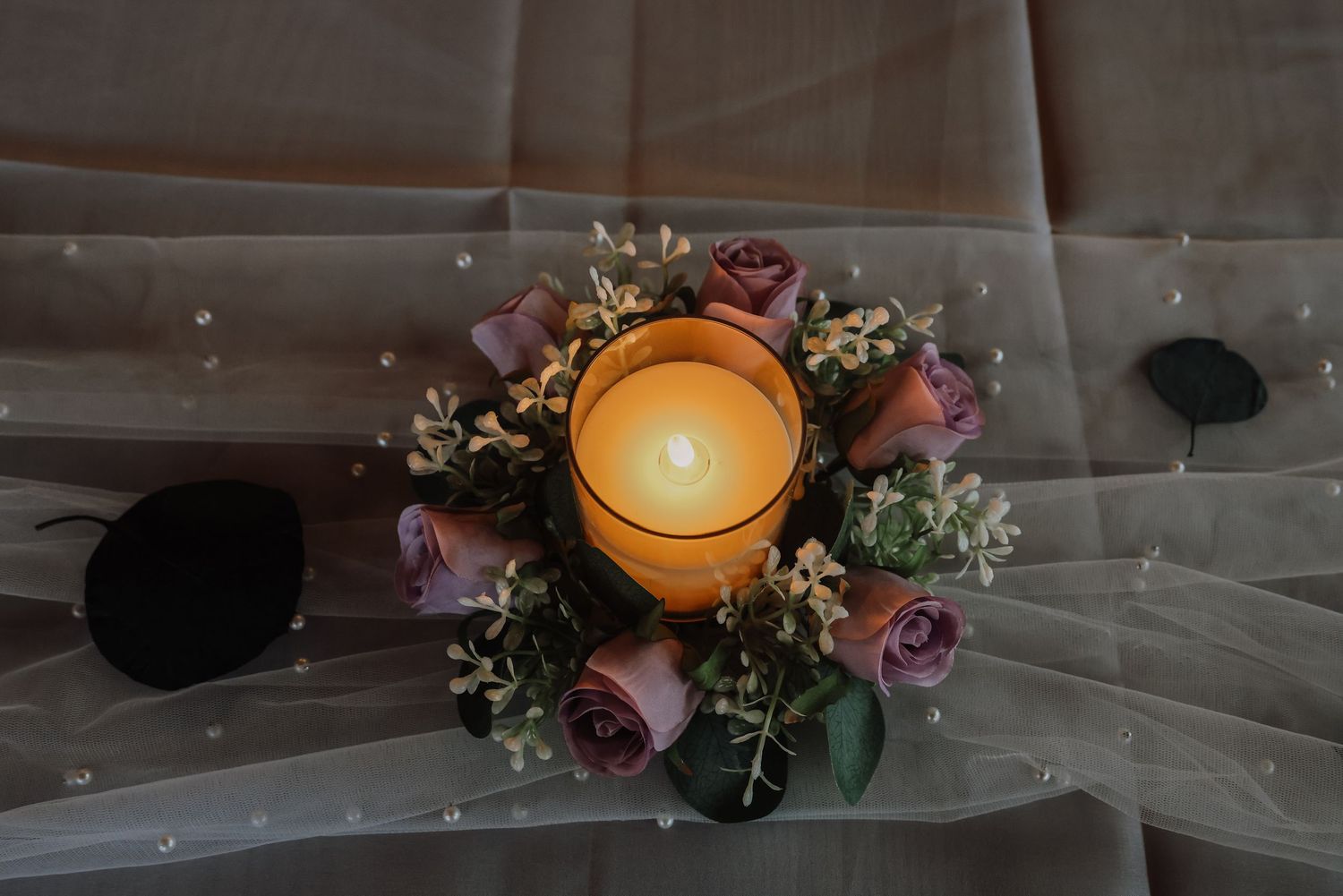 Elegant wedding decor with floating candles in glass vessels surrounded by delicate pink and white floral arrangements.