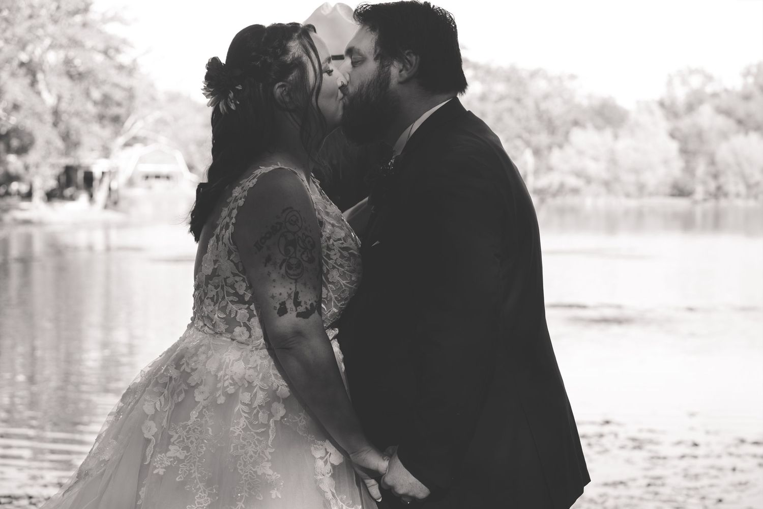 Black and white romantic engagement photos captured by a lake with soft natural lighting.