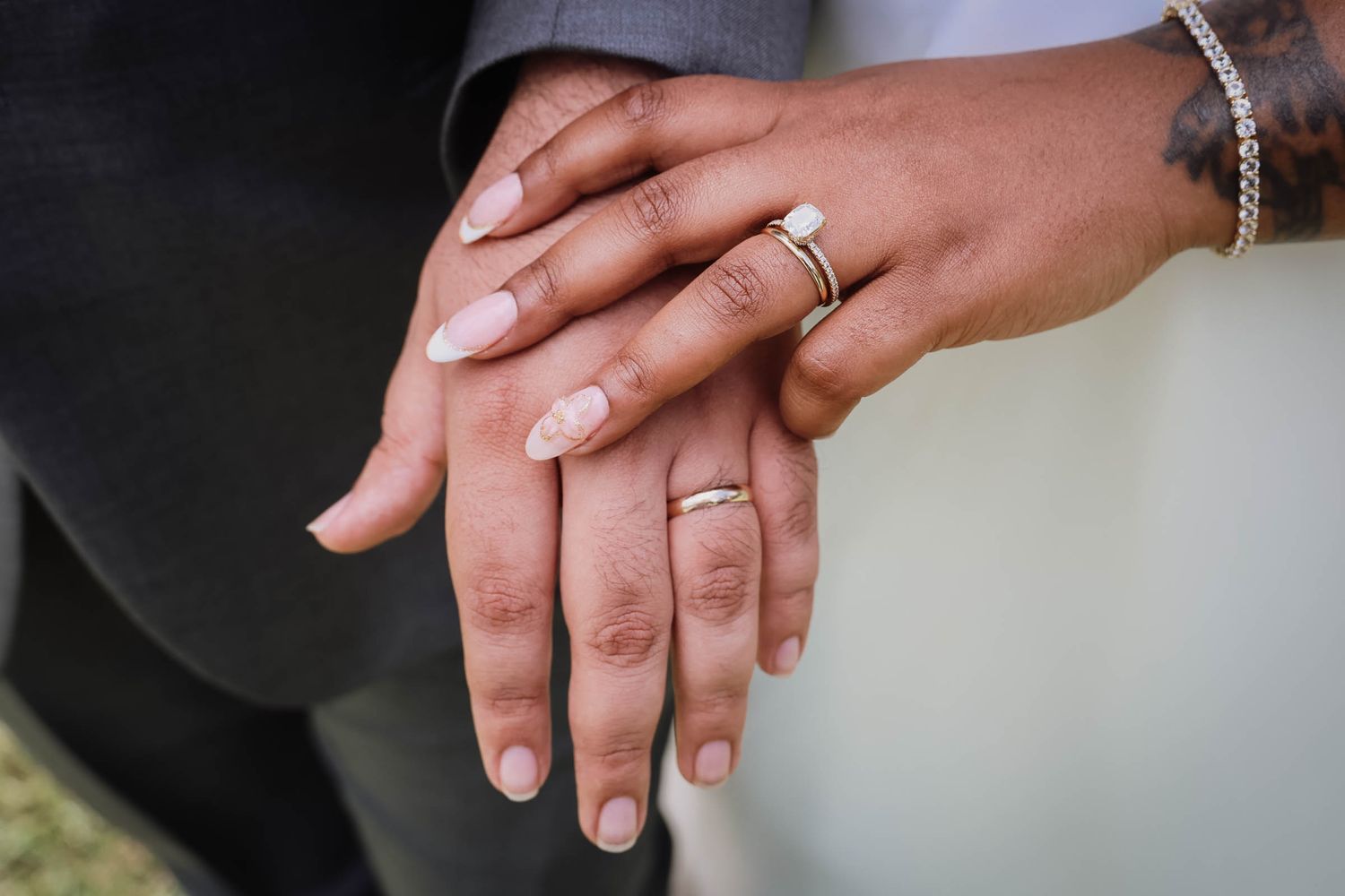 Two hands displaying wedding rings and an engagement ring, symbolizing marriage and commitment.