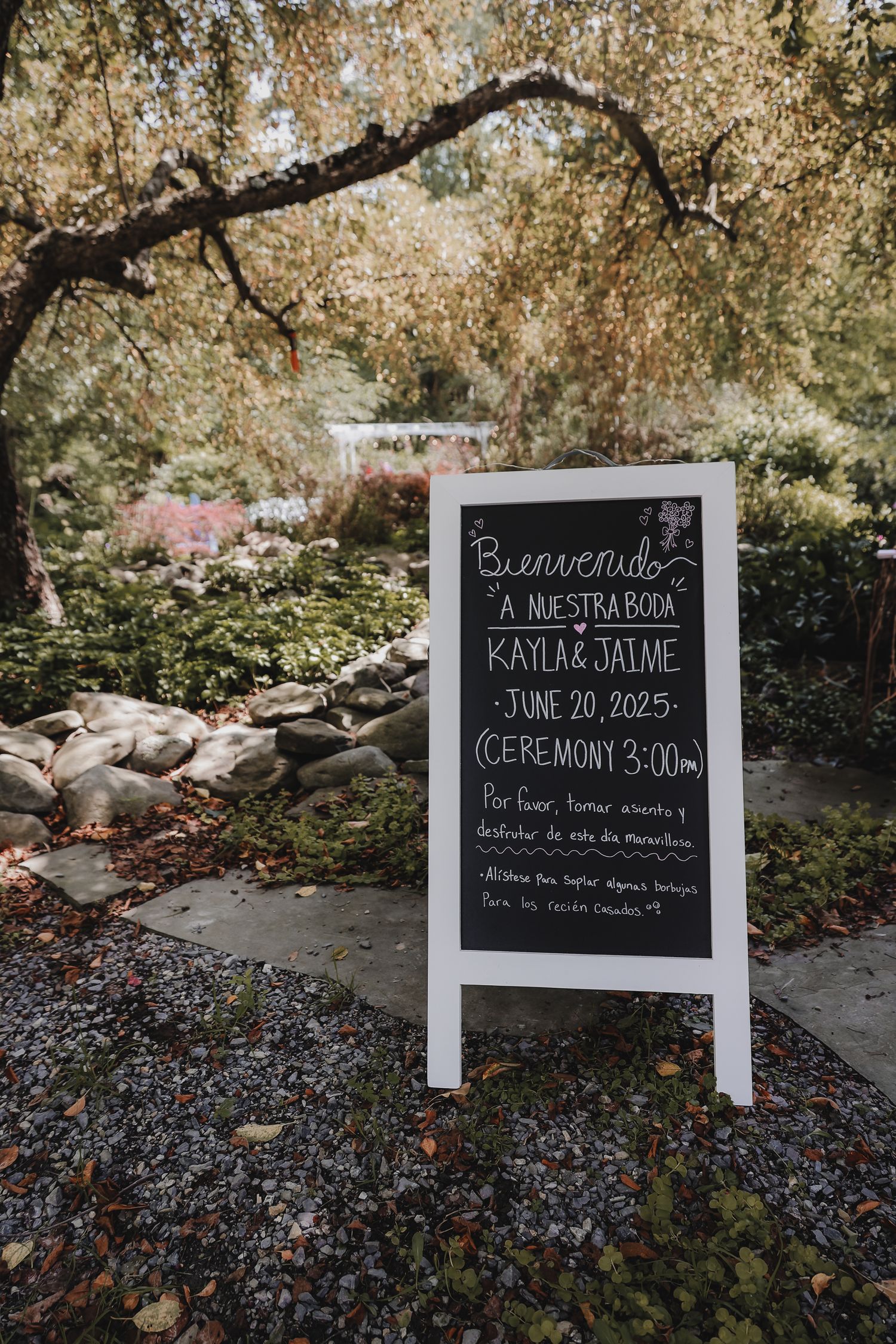 A series of outdoor wedding venue photos showing a rocky creek bed and chalkboard welcome signs under autumn trees.