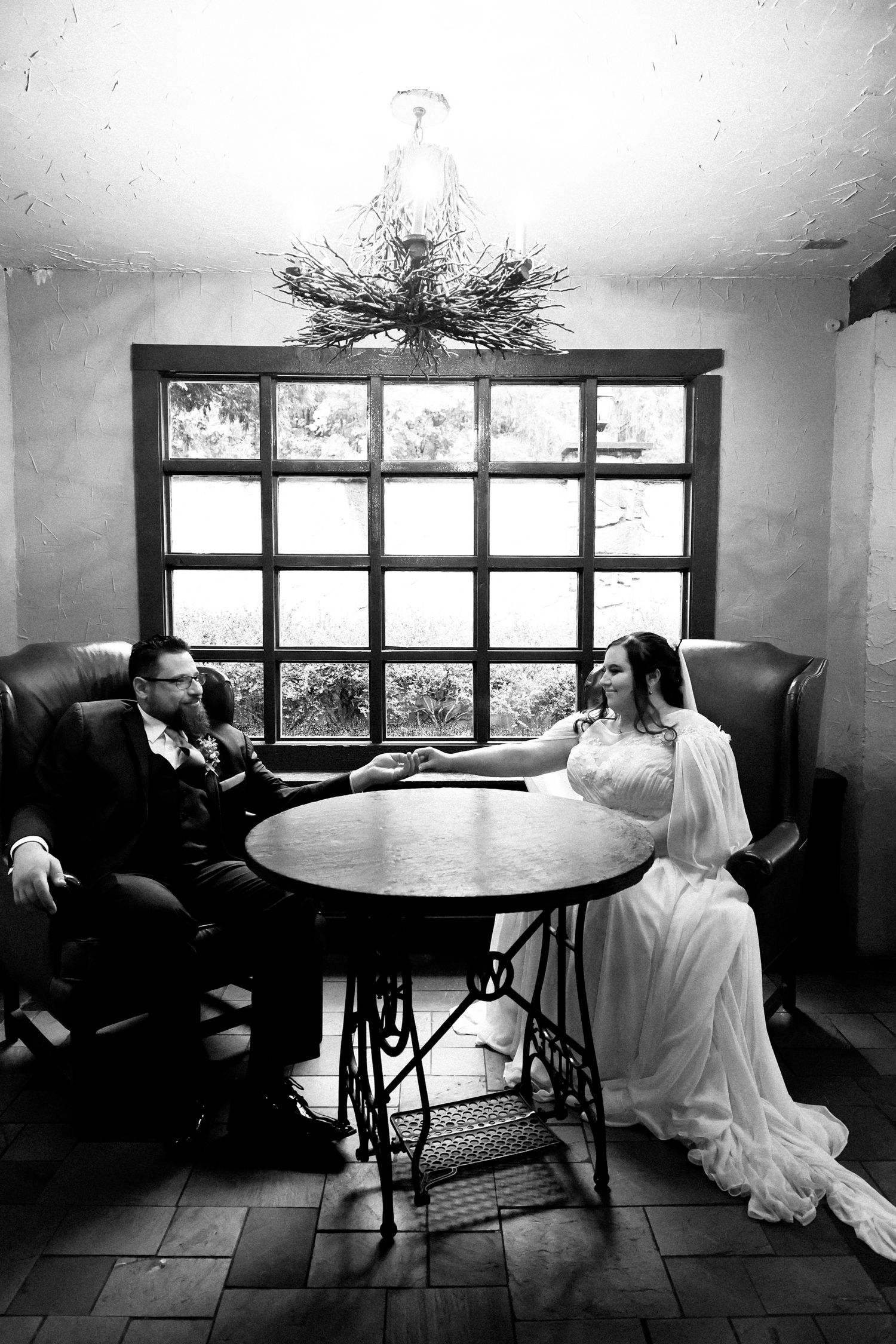 A black and white triptych series showing a bride in a wedding dress sitting alone at a round table near a window.